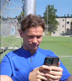 a man in a blue shirt is using a cell phone