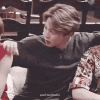 a man in a black shirt is holding a woman 's arm while sitting on a couch .
