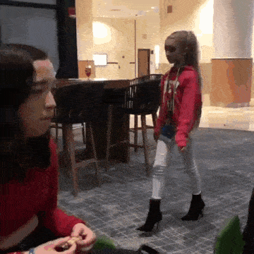 a girl in a red hoodie with the word ny on it is standing next to a woman