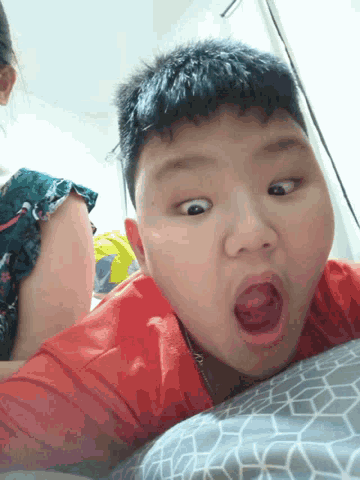 a young boy in a red shirt with his mouth open