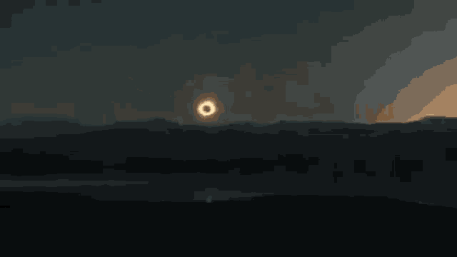 a partial eclipse of the sun is visible in the sky over a lake .