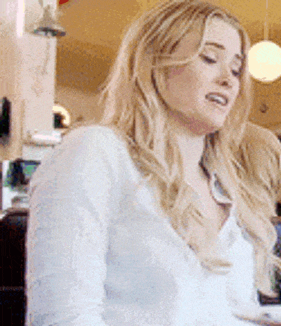 a woman with long blonde hair is sitting at a table in a restaurant and looking at the camera .