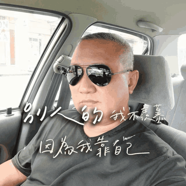 a man wearing sunglasses sits in a car with chinese writing on the side