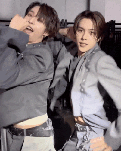 two men in suits are standing next to each other and one has a belt around his waist