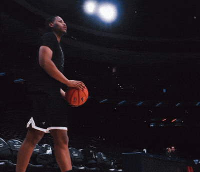 a man holding a basketball in a dark arena