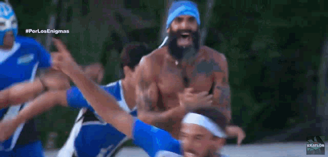 a man with a beard and a bandana on his head is surrounded by other men in blue shirts