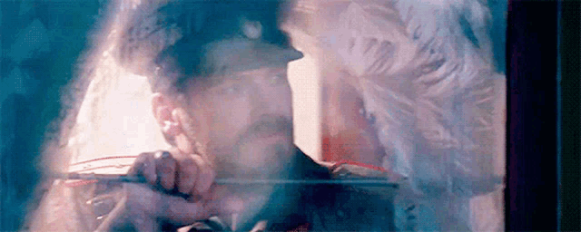 a man in a hat is looking out of a window at a woman in a white dress .