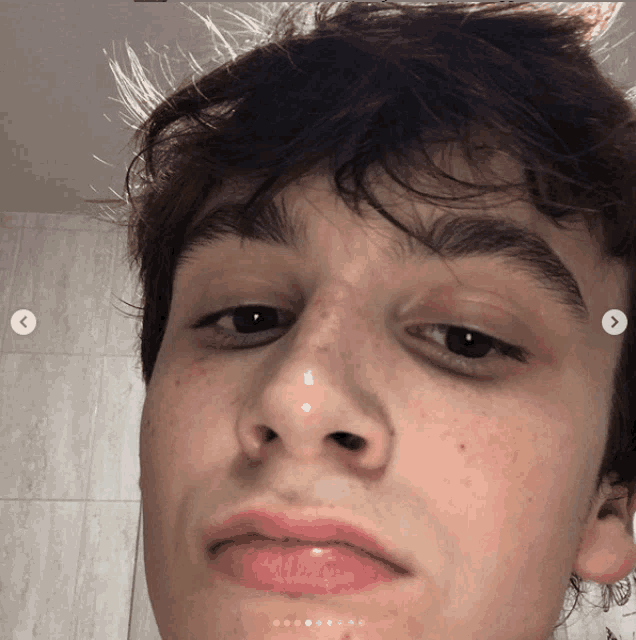 a close up of a young man 's face with a white x on the bottom right