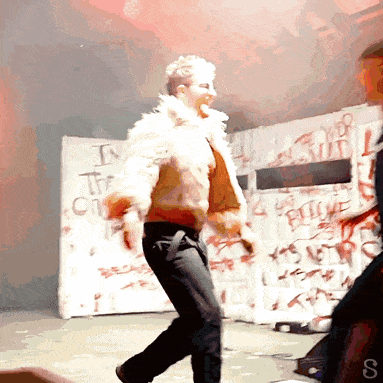 a woman in a fur coat is dancing in front of a wall that says i 'm the only one