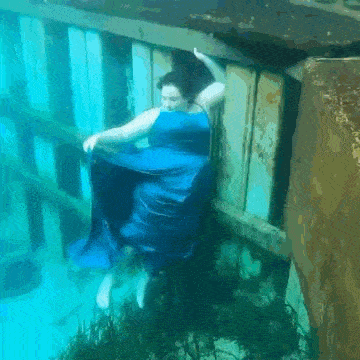 a woman in a blue dress is floating underwater