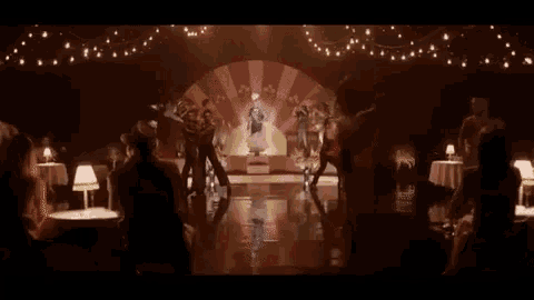 a group of people are dancing in a dark room in front of a large screen .