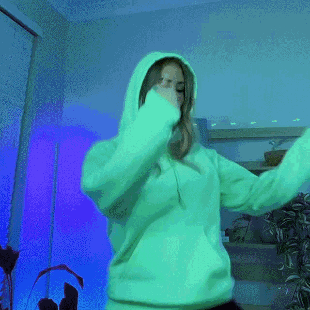 a woman wearing a white hoodie is dancing in a room