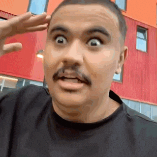 a man with a mustache is wearing a black shirt and making a funny face .