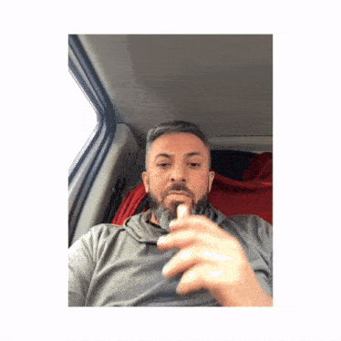 a man with a beard is sitting in the back of a car
