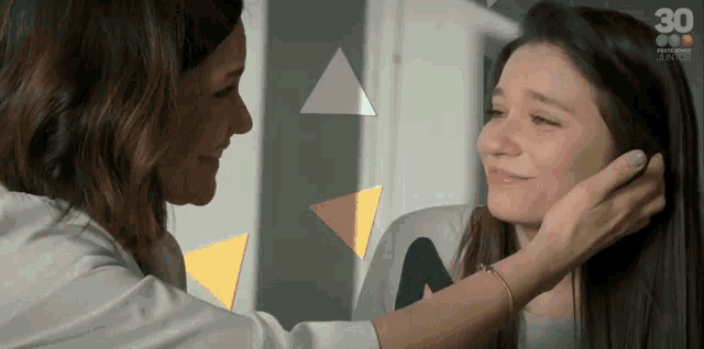 a woman is touching another woman 's hair with the number 30 on the bottom