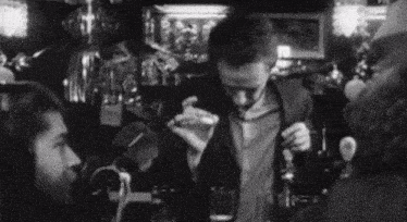a black and white photo of a man holding a bottle of perfume
