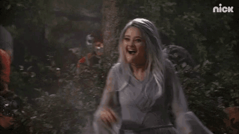 a woman in a ghost costume is standing in the woods .