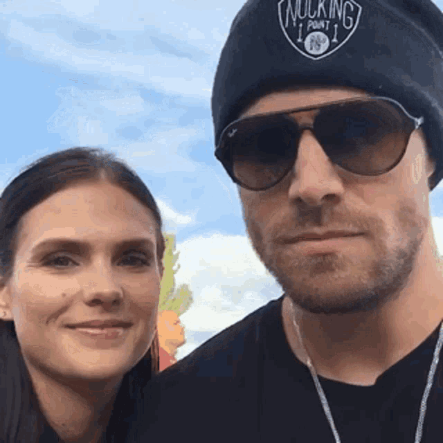 a man and a woman are posing for a picture and the man is wearing a beanie that says walking point