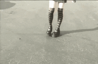 a black and white photo of a person wearing striped socks and shoes .