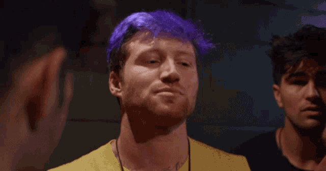 a man with purple hair has a tattoo on his neck that says ' a '