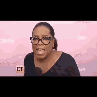 oprah winfrey is talking into a microphone and making a funny face .