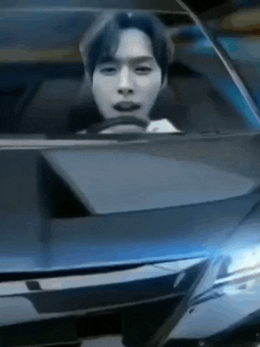 a man is driving a car with his mouth open and looking out the window .