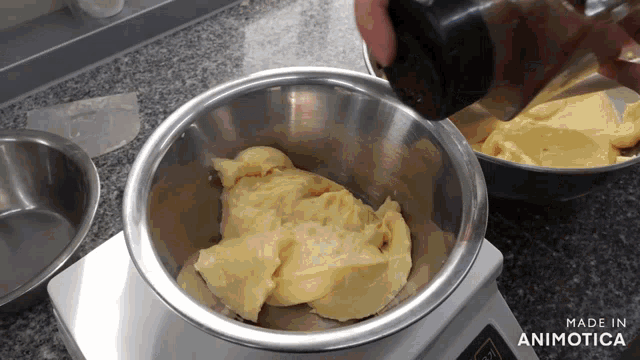 a person is pouring something into a metal bowl that says made in animotica on it