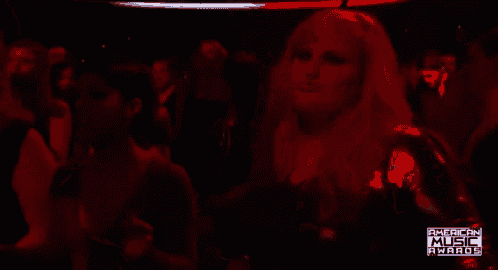 a woman is dancing in a crowd at an american music awards event