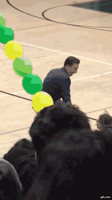 a man stands on a basketball court surrounded by balloons