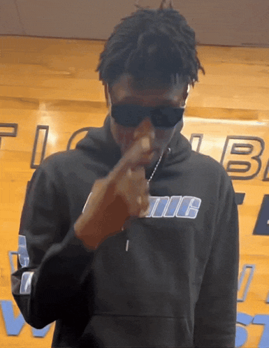 a man wearing sunglasses and a hoodie that says iic