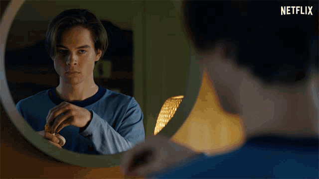 a young man looking at himself in a mirror with a netflix logo in the corner
