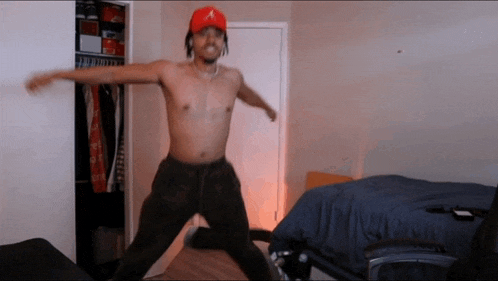 a shirtless man in a red hat is jumping in a room