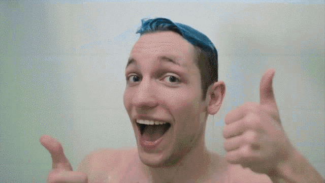 a young man with blue hair is giving a thumbs up