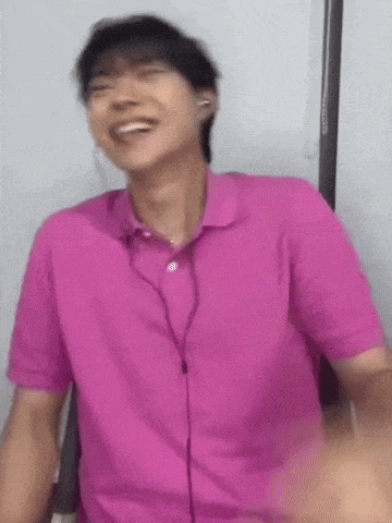 a man wearing a pink shirt and headphones is laughing and smiling .