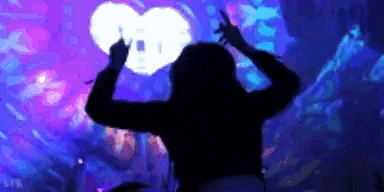 a silhouette of a woman dancing in front of a heart in a club .