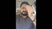 a man with a beard is giving the middle finger while sitting in the back seat of a car .