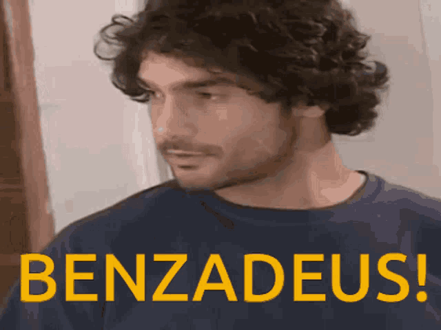a man with curly hair is wearing a blue shirt with benzadeus written on it