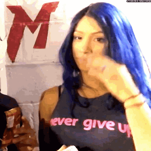 a woman with blue hair wears a shirt that says never give up