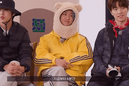 a man wearing a teddy bear hat is sitting next to two other people