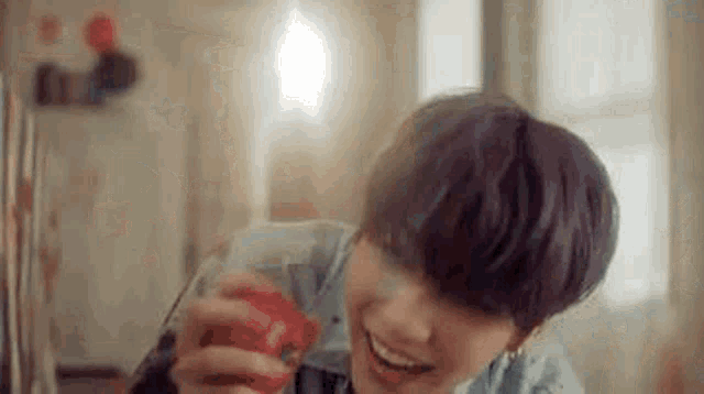 a young man with purple hair is smiling while holding a red object in his hand .