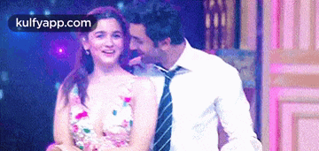 a man and a woman are dancing together on a stage and the man is kissing the woman on the cheek .