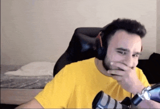 a man wearing headphones and a yellow shirt covering his mouth with his hand