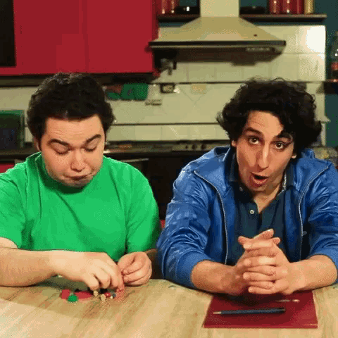 two men sitting at a table with their hands folded in front of them