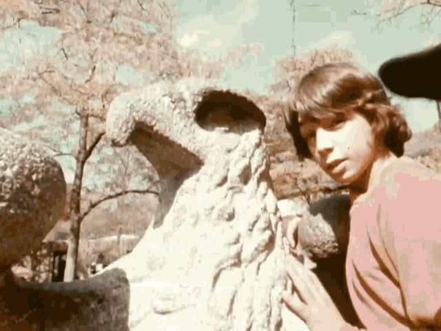 a young boy is touching a statue of a bird