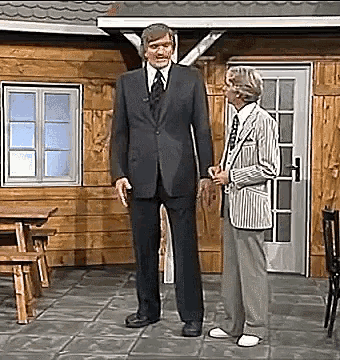 a man in a suit and tie stands next to another man