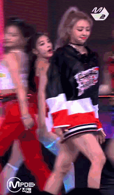 a group of girls are dancing on a stage and the letters mpd are visible
