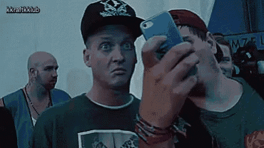a man taking a picture of himself with a cell phone with kkrafkklub written on the bottom right