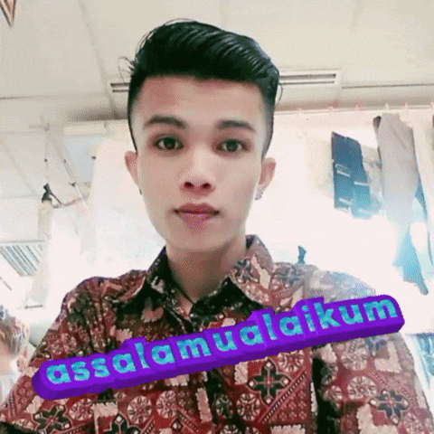 a young man wearing a shirt with a sticker that says assalamualaikum on it