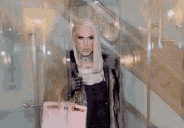 a woman in a fur coat is standing on a set of stairs holding a pink bag .
