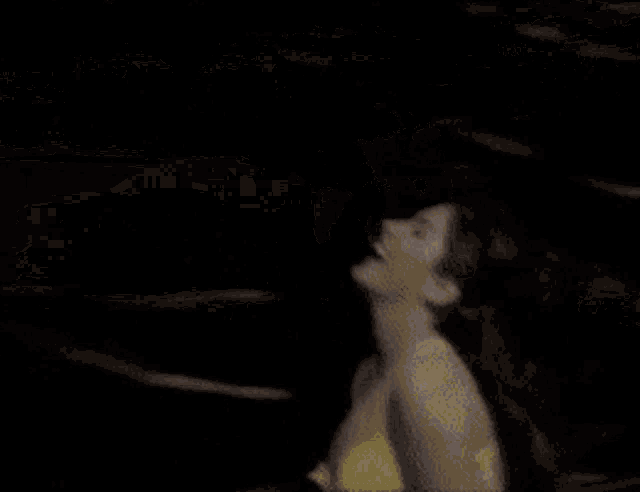 a woman in a yellow bikini is jumping into a body of water .